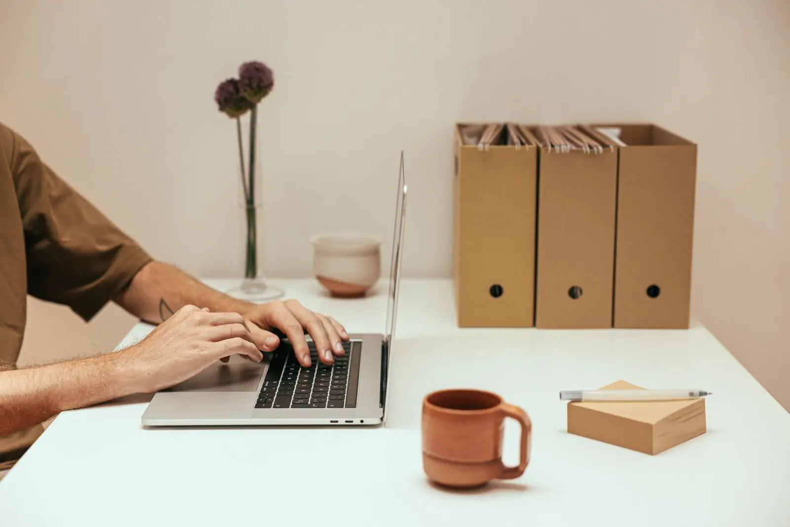 Hands typing on a laptop at a minimalist desk